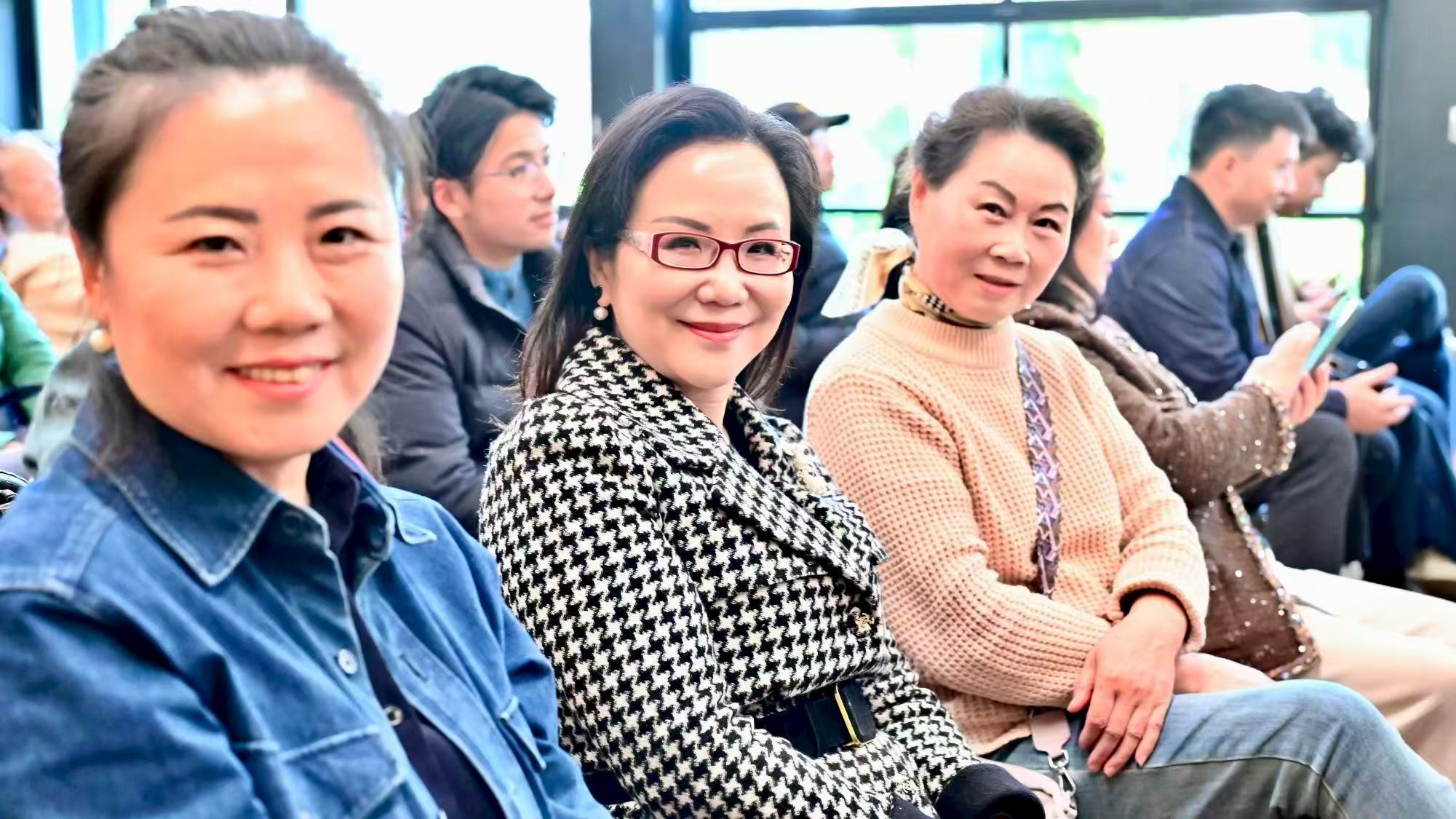 几位来宾在观众席上微笑合影