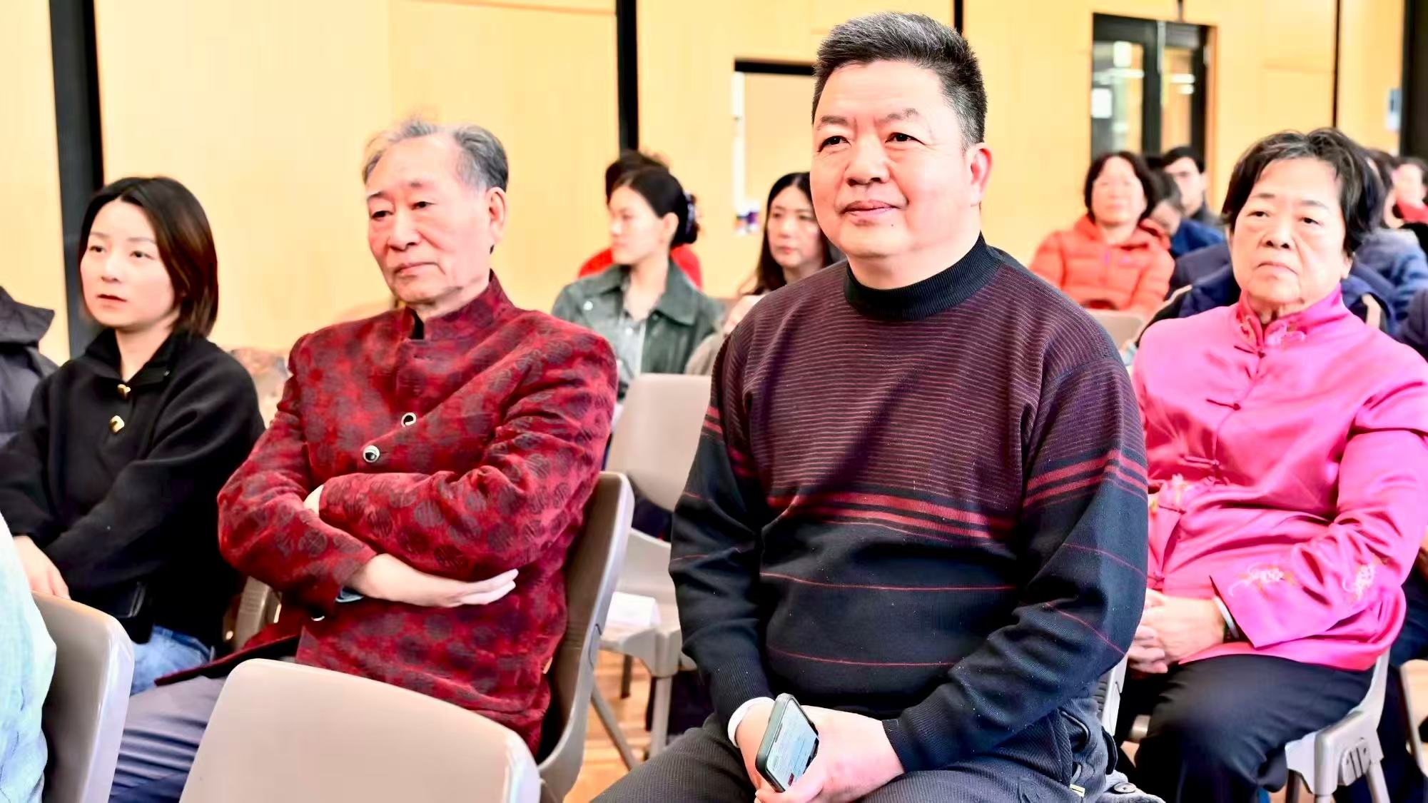 身穿红色、深色和粉色衣服的来宾在观众席上聆听