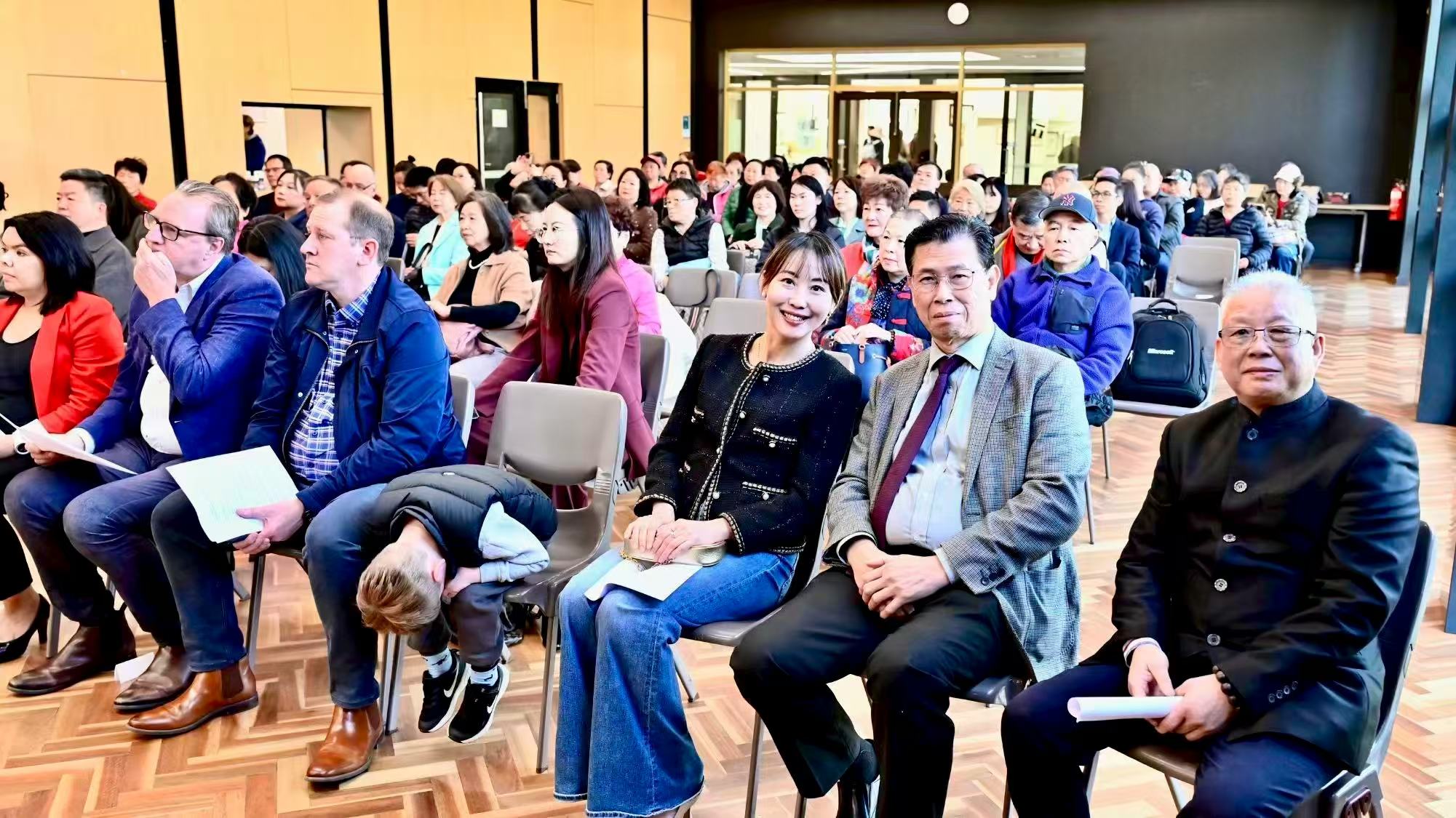 前排来宾面向镜头留影,后方坐着与会来宾